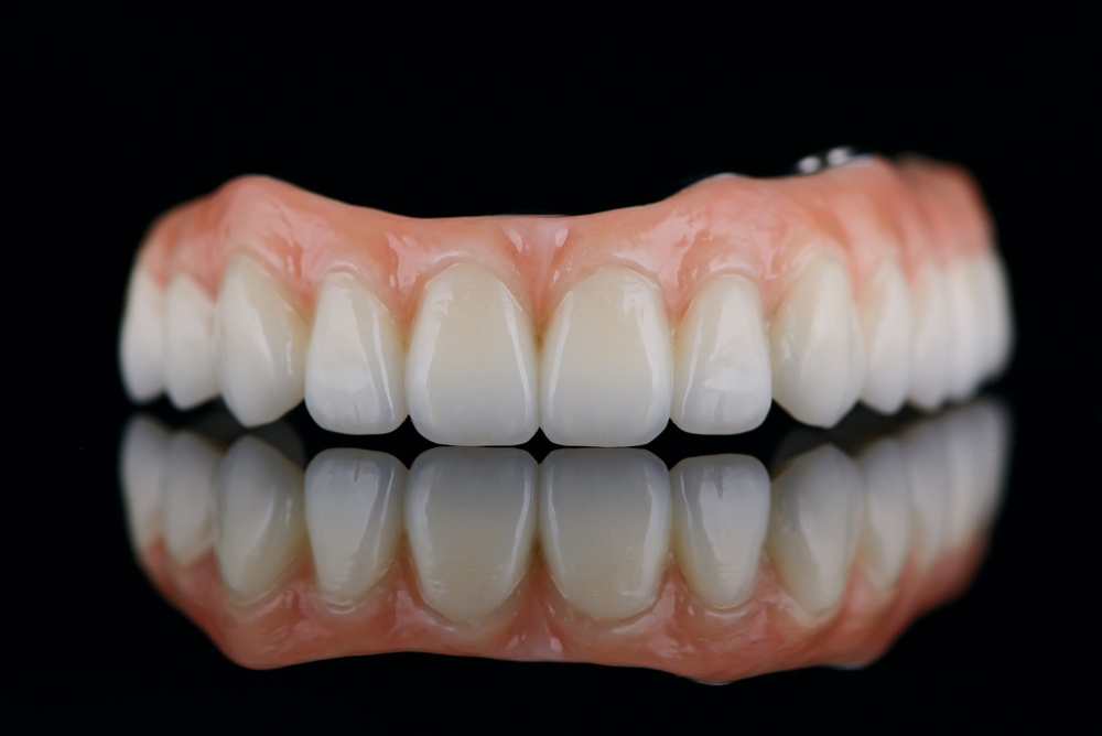 Image of a dentist smiling, pointing to a set of implant dentures in a patient's mouth, with the text "Full Mouth Implant Dentures: Are They Right For You?"